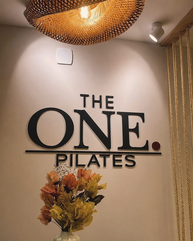 Recepção com o logo THE ONE Pilates e luminária de palha